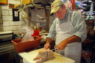 Terry Leu, owner of Rolston Poultry at the West Side Market, cuts up a fresh chicken at his stand on Friday, October 5, 2012, after a visit from President Barack Obama. Image courtesy of Brandon Blackwell, The Plain Dealer.